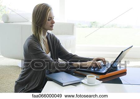 Stock Photo - Woman using laptop computer in living room. Fotosearch