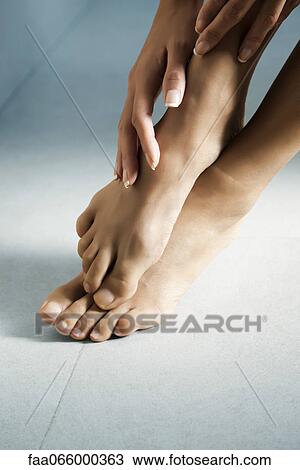 Woman's hand touching her bare feet View Large Photo Image Stock Image - Woman's hand touching her bare feet. Fotosearch