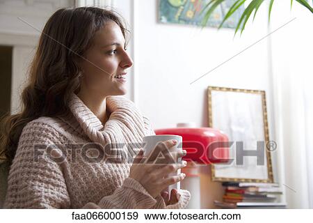 Young woman enjoying cup of coffee at home View Large Photo Image Stock Photo - Young woman enjoying cup of coffee at home. Fotosearch