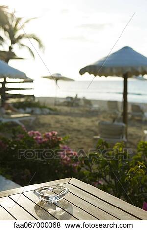 Ashtray on table at beach, beach umbrellas and deckchairs in background View Large Photo Image Stock Photo - Ashtray on table at beach, beach umbrellas and deckchairs in background. Fotosearch