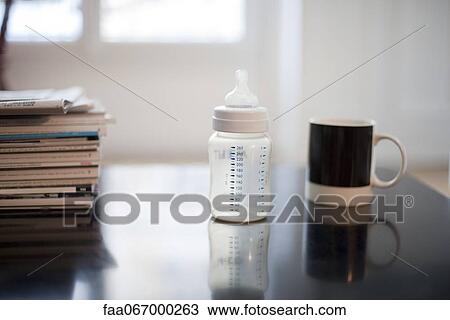 Stock Image - Baby bottle, coffee mug and stack of magazines. Fotosearch