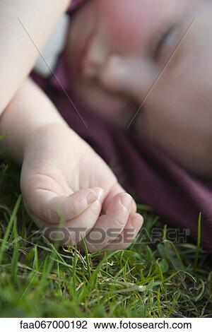 Stock Image - Baby girl napping on grass. Fotosearch