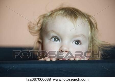Stock Photo - Baby girl peering over side of crib, portrait. Fotosearch