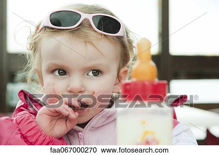 Stock Image - Baby girl with messy face, portrait. Fotosearch