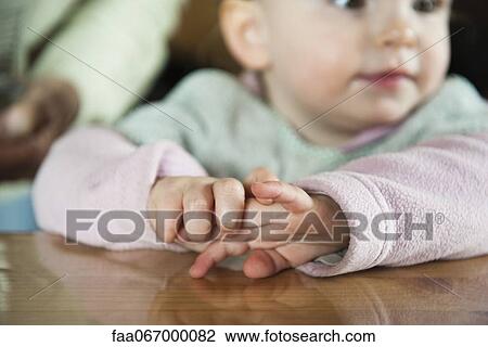 Stock Image - Baby girl's clasped hands. Fotosearch