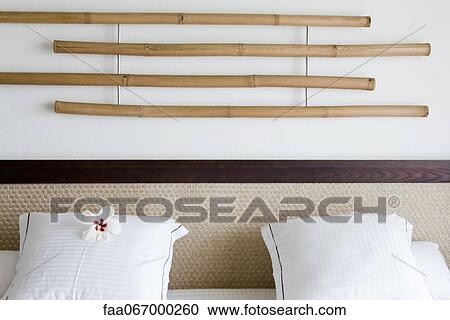 Bamboo decoration hanging on wall above headboard, white hibiscus flower head on pillow View Large Photo Image Stock Image - Bamboo decoration hanging on wall above headboard, white hibiscus flower head on pillow. Fotosearch