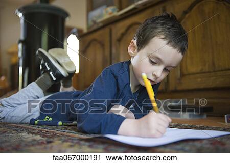 Boy lying on floor, writing on paper with pencil View Large Photo Image Stock Image - Boy lying on floor, writing on paper with pencil. Fotosearch