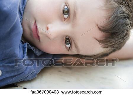 Stock Image - Boy resting head on arm, portrait. Fotosearch