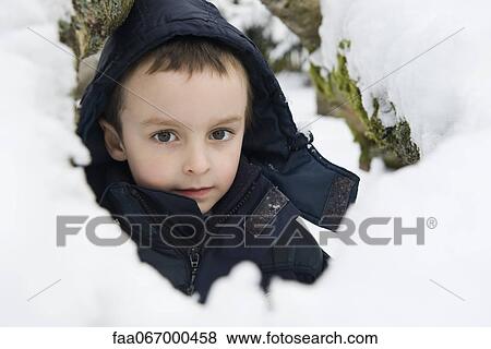Stock Photo - Boy sitting in snow, portrait. Fotosearch