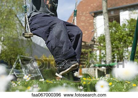 Boy sitting on swing, low section View Large Photo Image Stock Photograph - Boy sitting on swing, low section. Fotosearch