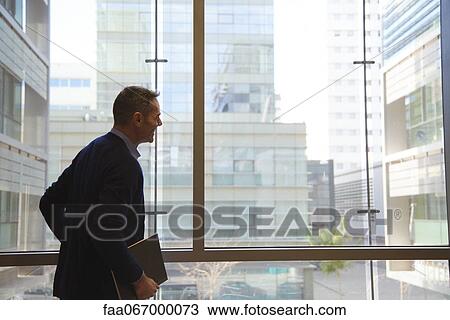 Stock Image - Businessman looking through window. Fotosearch