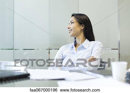 Stock Photograph - Businesswoman with arms folded, looking away in thought. Fotosearch