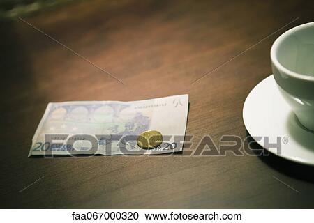 Stock Image - Empty coffee cup and money on table. Fotosearch