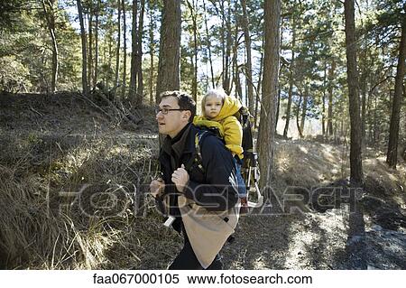 Stock Photography - Father hiking in woods with baby daughter in backpack carrier. Fotosearch