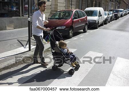 Father pushing toddler son in stroller View Large Photo Image Stock Photo - Father pushing toddler son in stroller. Fotosearch