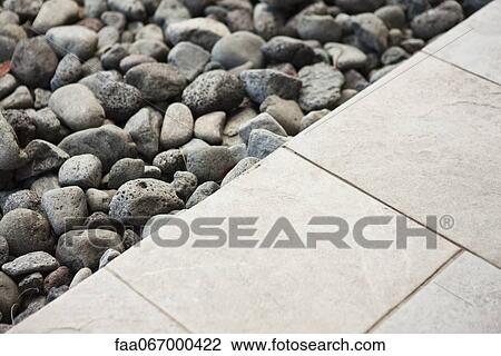 Stock Image - Gravel along edge of tiled patio. Fotosearch