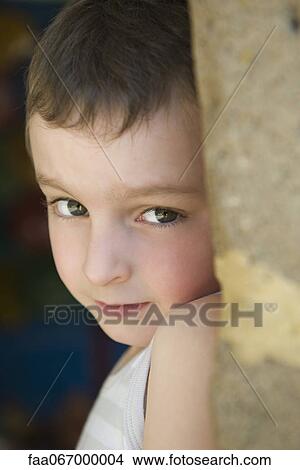 Picture - Little boy leaning against tree trunk, portrait. Fotosearch