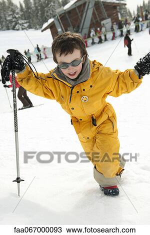 Stock Image - Little boy walking up ski slope. Fotosearch