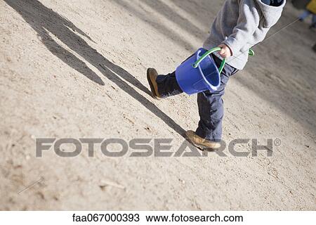 Little boy walking with sand bucket View Large Photo Image Stock Image - Little boy walking with sand bucket. Fotosearch
