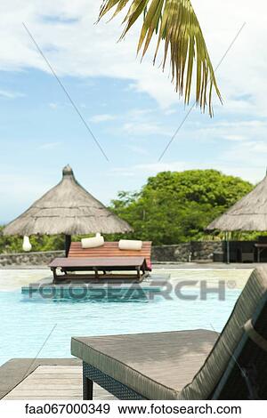 Stock Photo - Lounge chair beside pool at resort. Fotosearch