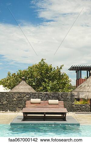 Stock Image - Lounge chairs in resort swimming pool. Fotosearch