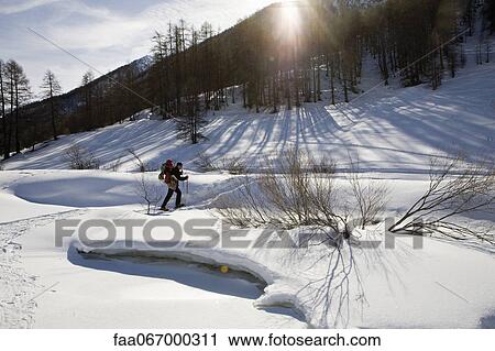 Stock Image - Man snowshoeing, carrying child in baby carrier. Fotosearch