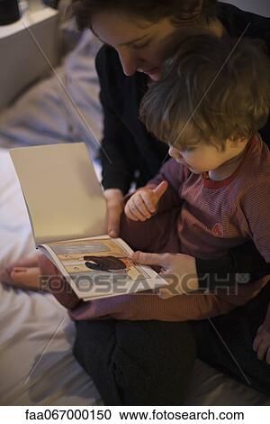 Mother holding toddler son on lap, reading bedtime story View Large Photo Image Stock Image - Mother holding toddler son on lap, reading bedtime story. Fotosearch