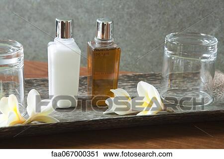 Stock Image - Perfume bottle and glasses on tray with frangipani flowers. Fotosearch
