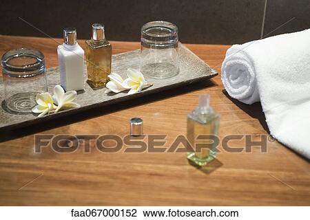 Stock Image - Perfume bottles and frangipani flowers on tray. Fotosearch
