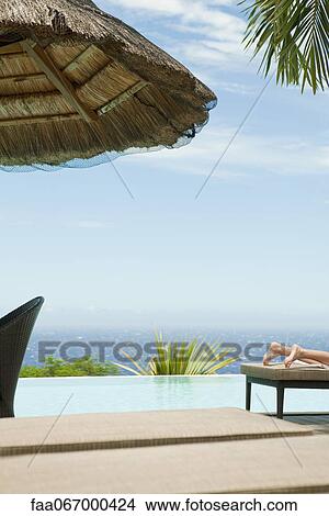 Picture - Person sunbathing at seaside resort. Fotosearch