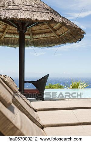 Stock Image - Poolside lounge chairs at seaside resort. Fotosearch