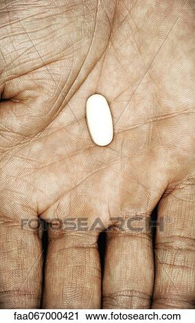 Stock Image - Single pill in hand. Fotosearch