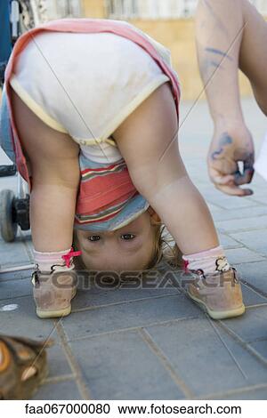 Toddler girl bending over, peeking through legs at camera View Large Photo Image Stock Image - Toddler girl bending over, peeking through legs at camera. Fotosearch