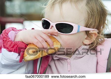 Stock Photo - Toddler girl eating baguette. Fotosearch