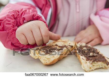 Toddler girl eating baguette with chocolate spread, cropped View Large Photo Image Stock Photo - Toddler girl eating baguette with chocolate spread, cropped. Fotosearch