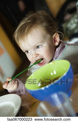 Stock Image - Toddler girl feeding herself with spoon. Fotosearch