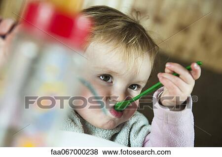 Stock Photo - Toddler girl feeding herself with spoon. Fotosearch