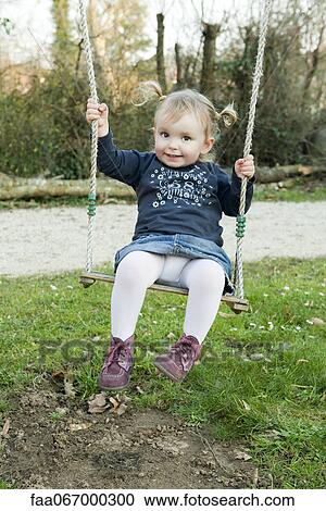 Stock Image - Toddler girl on swing, portrait. Fotosearch