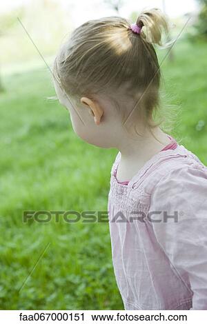 Stock Image - Toddler girl outdoors, looking over shoulder. Fotosearch