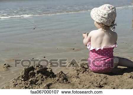 Toddler girl playing in sand at the beach, rear view View Large Photo Image Stock Photo - Toddler girl playing in sand at the beach, rear view. Fotosearch