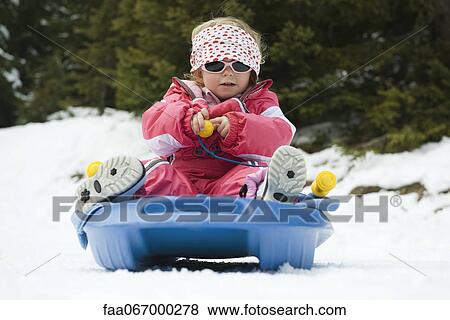 Stock Photo - Toddler girl sitting on sled. Fotosearch