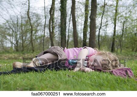 Stock Image - Toddler girl taking a nap outdoors. Fotosearch