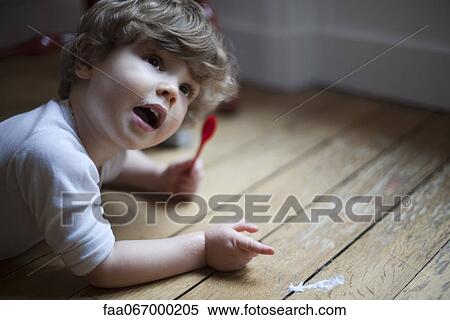 Toddler lying on floor with spoon in hand, pointing to spilled food View Large Photo Image Stock Photography - Toddler lying on floor with spoon in hand, pointing to spilled food. Fotosearch