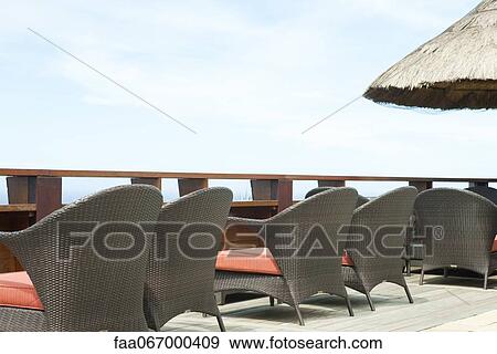 Stock Photo - Wicker chairs lined up along deck. Fotosearch