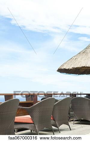 Stock Photograph - Wicker chairs lined up along deck. Fotosearch
