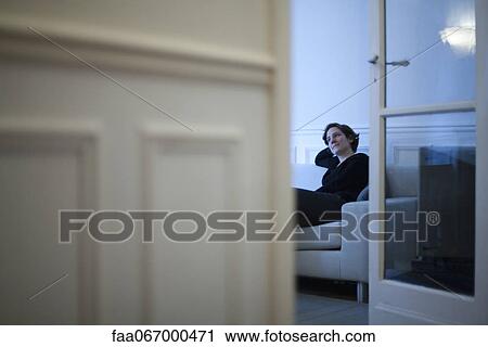 Stock Image - Woman relaxing on sofa. Fotosearch
