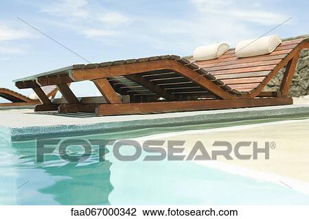 Wooden lounge chairs overlooking swimming pool View Large Photo Image Stock Image - Wooden lounge chairs overlooking swimming pool. Fotosearch