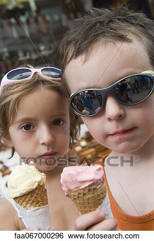 Stock Photograph - Young siblings eating ice cream cones. Fotosearch