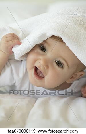 Stock Photo - Baby peeking out from under blanket, portrait. Fotosearch