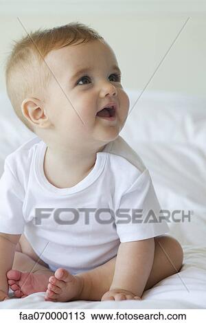 Baby sitting on bed, looking up, portrait View Large Photo Image Stock Image - Baby sitting on bed, looking up, portrait. Fotosearch